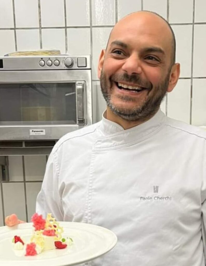 Chef sorride mostrando dessert creativo in cucina
